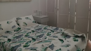 A bedroom with a bed, a nightstand, a wardrobe, and a wall-mounted artwork. - Apartment 'Apartmento La Palmera' with Wi-Fi and Air Conditioning (Tarifa)