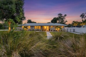 A single-story house with a flat roof, a front porch, and a pathway leading to the entrance. - The Ringling House - Sarasota's Best-Located Home - 3 bedrooms. Sleeps 7. Downtown walkable. Legacy Trail at your door. Lido Key Beach 4.5 miles away. (Sarasota)