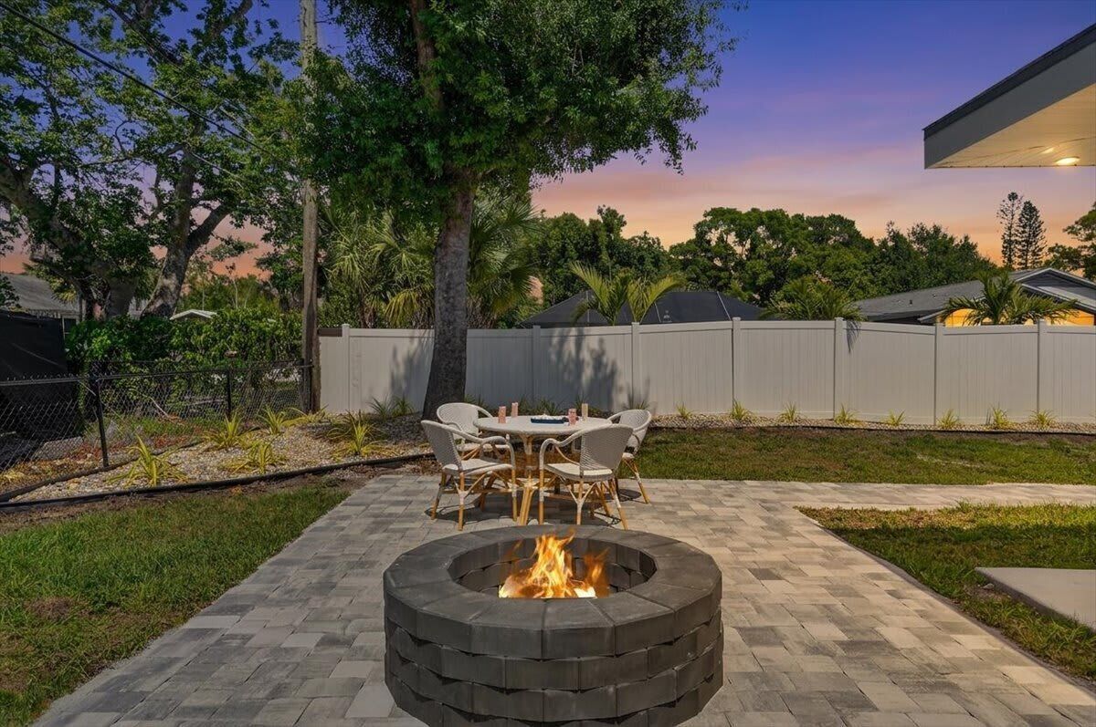 A backyard with a circular fire pit, outdoor furniture, and a fence.
