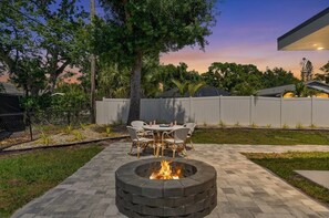 A backyard with a circular fire pit, outdoor furniture, and a fence. - The Ringling House - Sarasota's Best-Located Home - 3 bedrooms. Sleeps 7. Downtown walkable. Legacy Trail at your door. Lido Key Beach 4.5 miles away. (Sarasota)