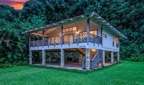 Ein zweistöckiges Haus mit Balkon, umgeben von üppiger Vegetation.