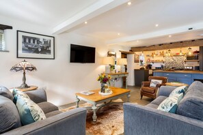 Een moderne woonkamer met een zithoek, een salontafel en een televisie.