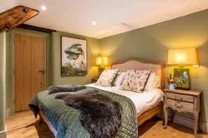 A bedroom with a bed, two bedside lamps, a wooden nightstand, and a door.