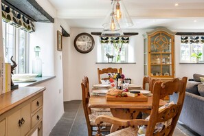 Een eetgedeelte met een houten tafel, gedekt voor vier personen, omringd door houten stoelen.
