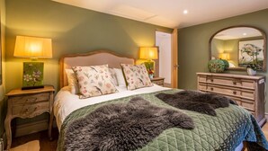 Ein Schlafzimmer mit einem Bett, Nachttischen, einem Schminktisch und einem Spiegel.