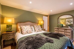Een slaapkamer met een bed, nachtkastjes, een dressoir en een spiegel.