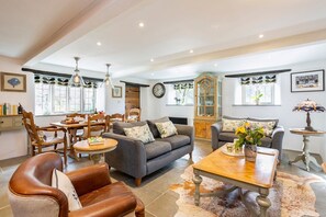 A spacious living room with a sofa, chairs, a coffee table, and a dining area with a table and chairs.