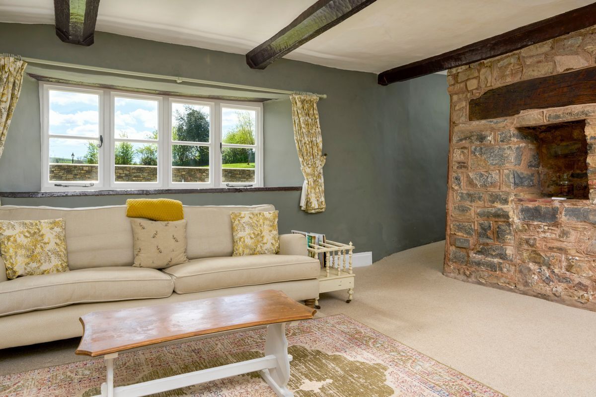A living room with a sofa, a coffee table, a stone fireplace, and a window with curtains.