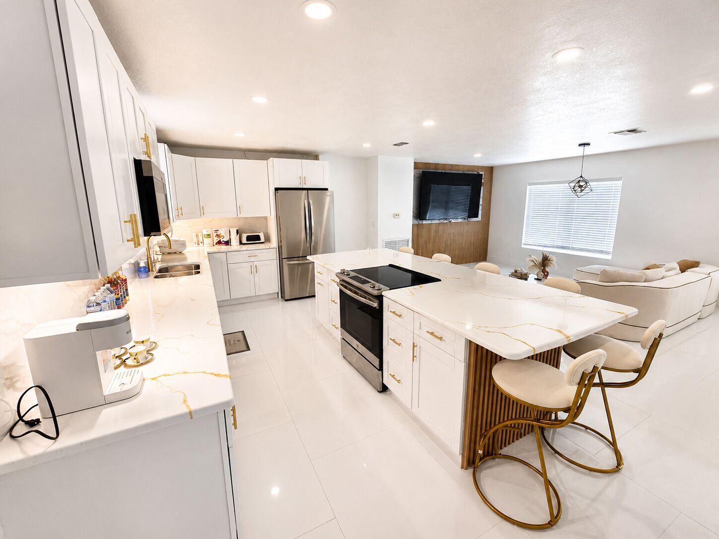 A modern kitchen with white cabinetry, stainless steel appliances, and a central island with bar stools.
