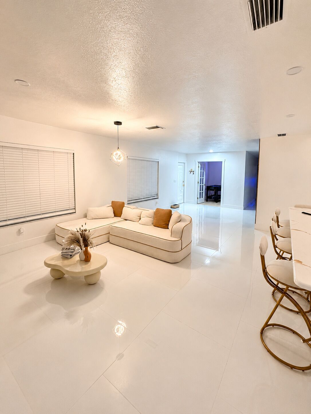 A modern living room with a sectional sofa, a coffee table, and a dining area with chairs.
