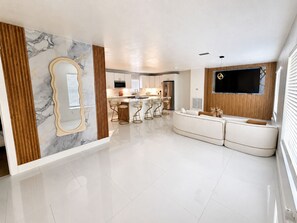 Una cocina moderna con salpicadero de mármol, una isla central con taburetes y un televisor integrado.