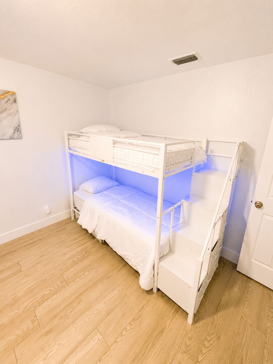 A bunk bed in a room with wooden flooring and white walls.