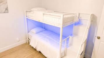 A bunk bed in a room with wooden flooring and white walls.