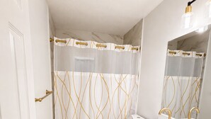 A bathroom with a white vanity, gold fixtures, and a shower curtain with a gold pattern. - Elegant 4BR Retreat Near Tampa with Private Office (Brandon)