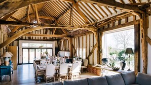 A rustic dining area with wooden beams, a large window, and a sofa.
