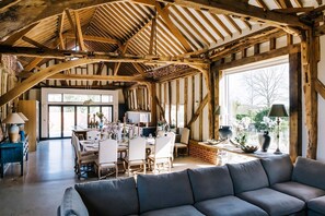 A rustic dining area with wooden beams, a large window, and a sofa.