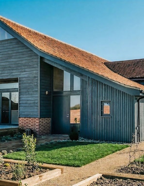 Una casa moderna con techo inclinado, ventanas amplias y base de ladrillo.