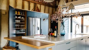 A modern kitchen with a central island, built-in wine rack, and a large window.