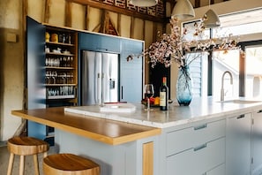 A modern kitchen with a central island, built-in wine rack, and a large window.