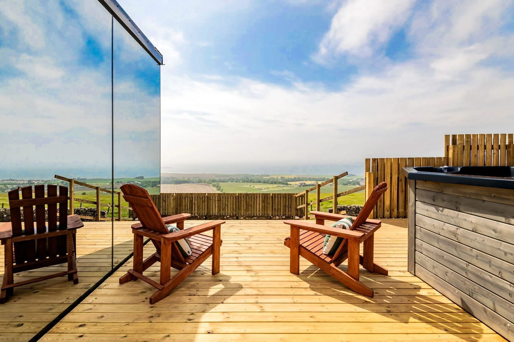A wooden deck with two rocking chairs and a hot tub.