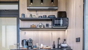 Une cuisine moderne dotée d’un plan de travail foncé, d’un four à micro-ondes, d’une machine à café et d’un grille-pain.
