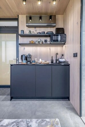 Eine moderne Küche mit dunkler Arbeitsplatte, einer Mikrowelle, einer Kaffeemaschine und einem Toaster.
