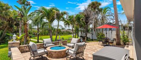 Un patio al aire libre con un brasero, asientos y vistas de un paisaje exuberante.