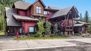 Un grand bâtiment en bois à plusieurs étages, doté d’un escalier imposant et d’une borne d’incendie rouge bien visible au premier plan.