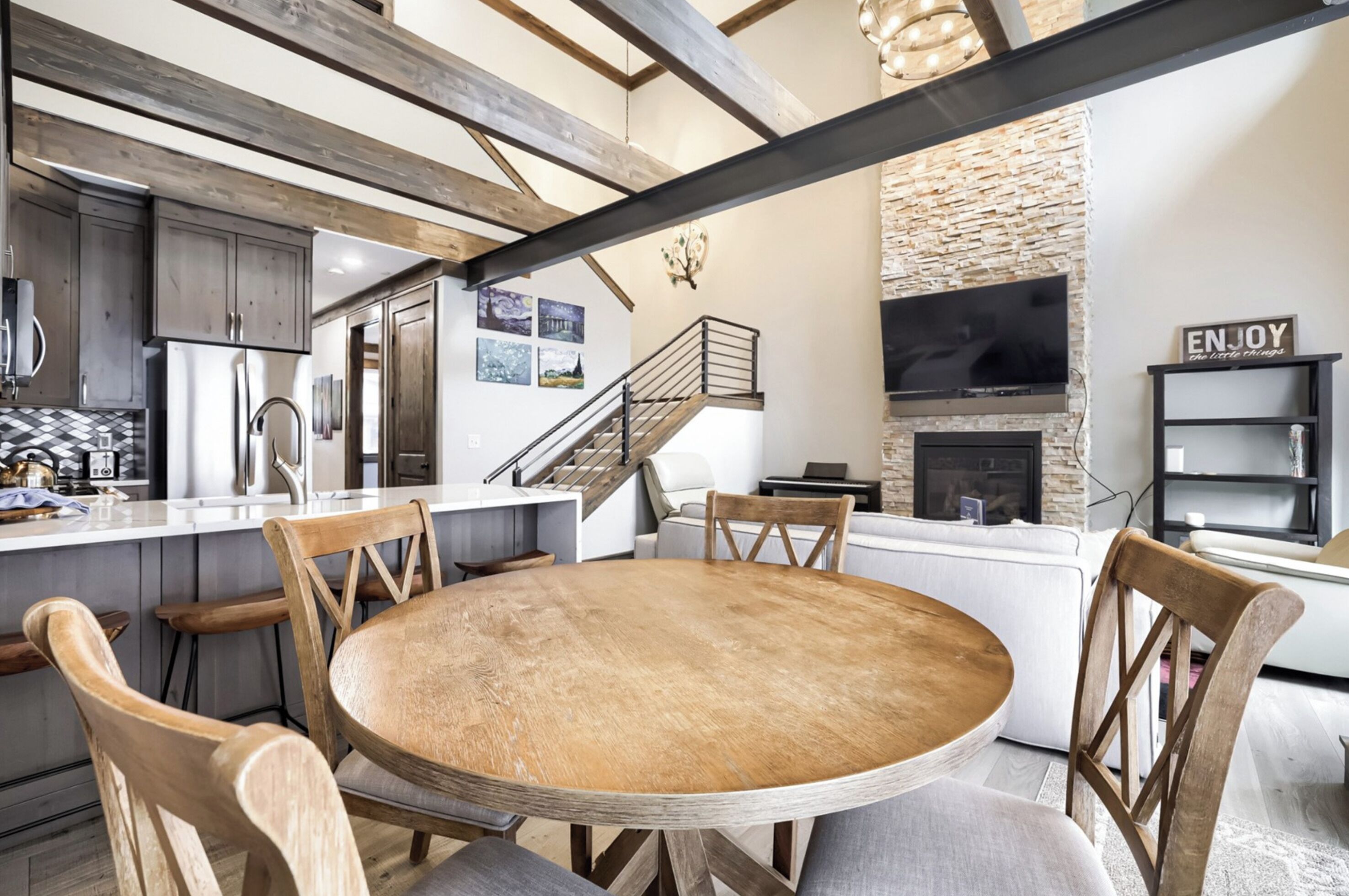 Een moderne keuken met een centraal eiland, houten stoelen en een ronde tafel.