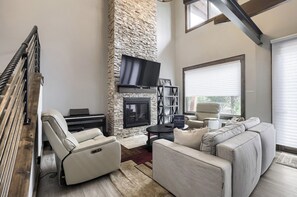 Una sala de estar moderna con chimenea de piedra, televisor de pantalla plana, piano y sofá.