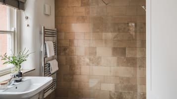 A bathroom with a white sink, a towel rack, and a shower with a tiled wall.