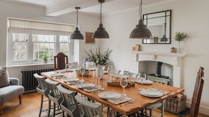 Uma sala de jantar com mesa de madeira posta para seis pessoas, rodeada por seis cadeiras.