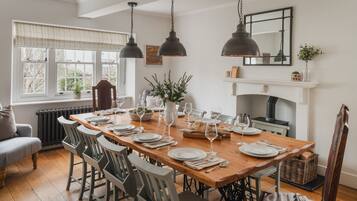 A dining room with a wooden table set for six, surrounded by six chairs.