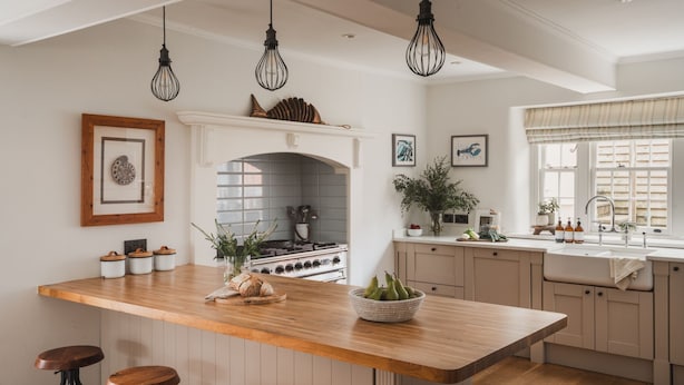 Cozinha moderna com ilha central, banquetas, fogão e janela com cortinas.