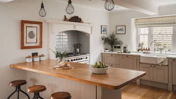 A modern kitchen with a central island, bar stools, a stove, and a window with curtains.