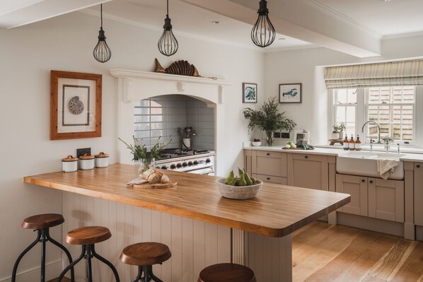 Een moderne keuken met een centraal eiland, barstoelen, een fornuis en een raam met gordijnen.
