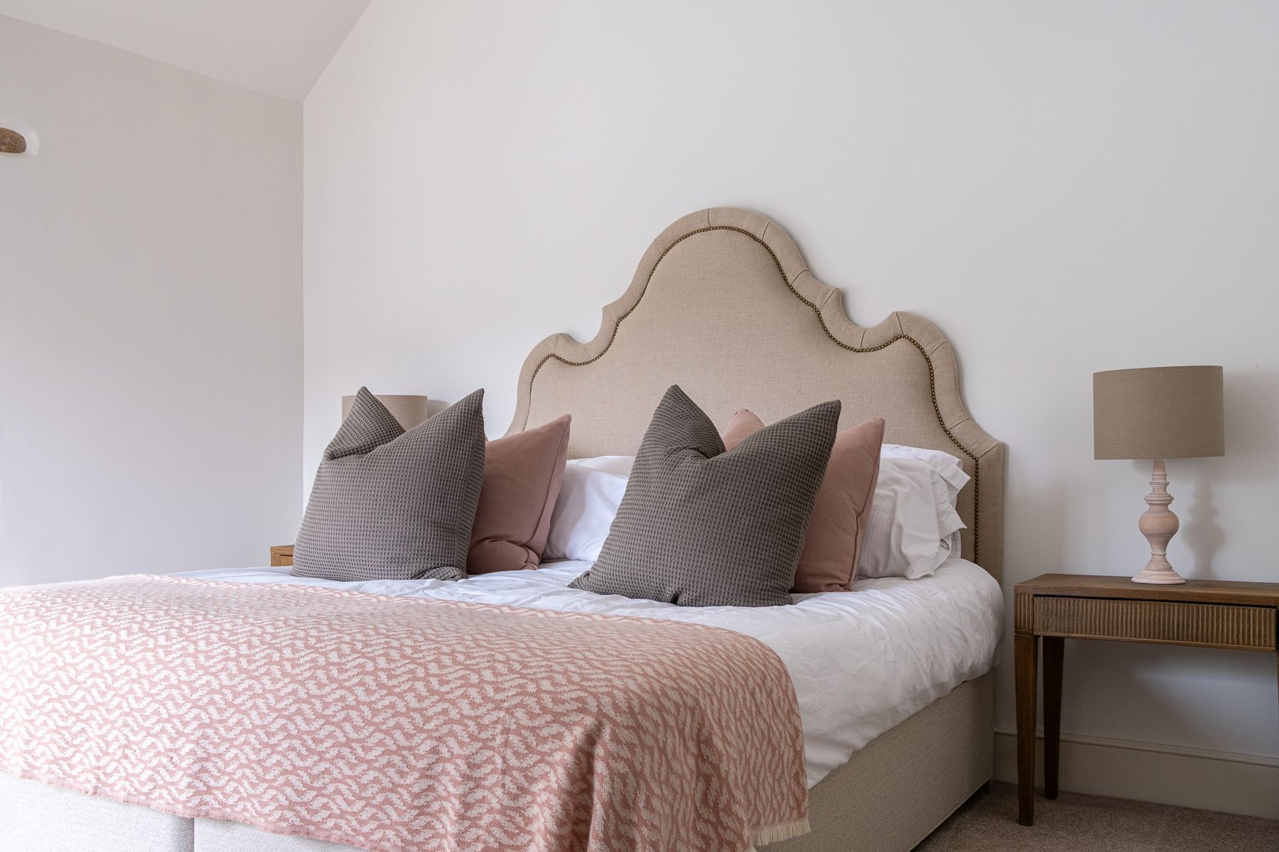 A neatly made bed with a patterned blanket and several pillows.