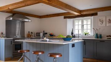 Een keuken met een centraal eiland, barkrukken, een ingebouwde oven en een groot raam.