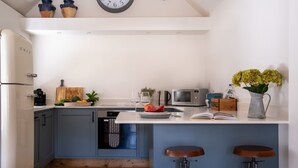 Uma cozinha moderna com ilha central, banquetas, máquina de café e micro-ondas.