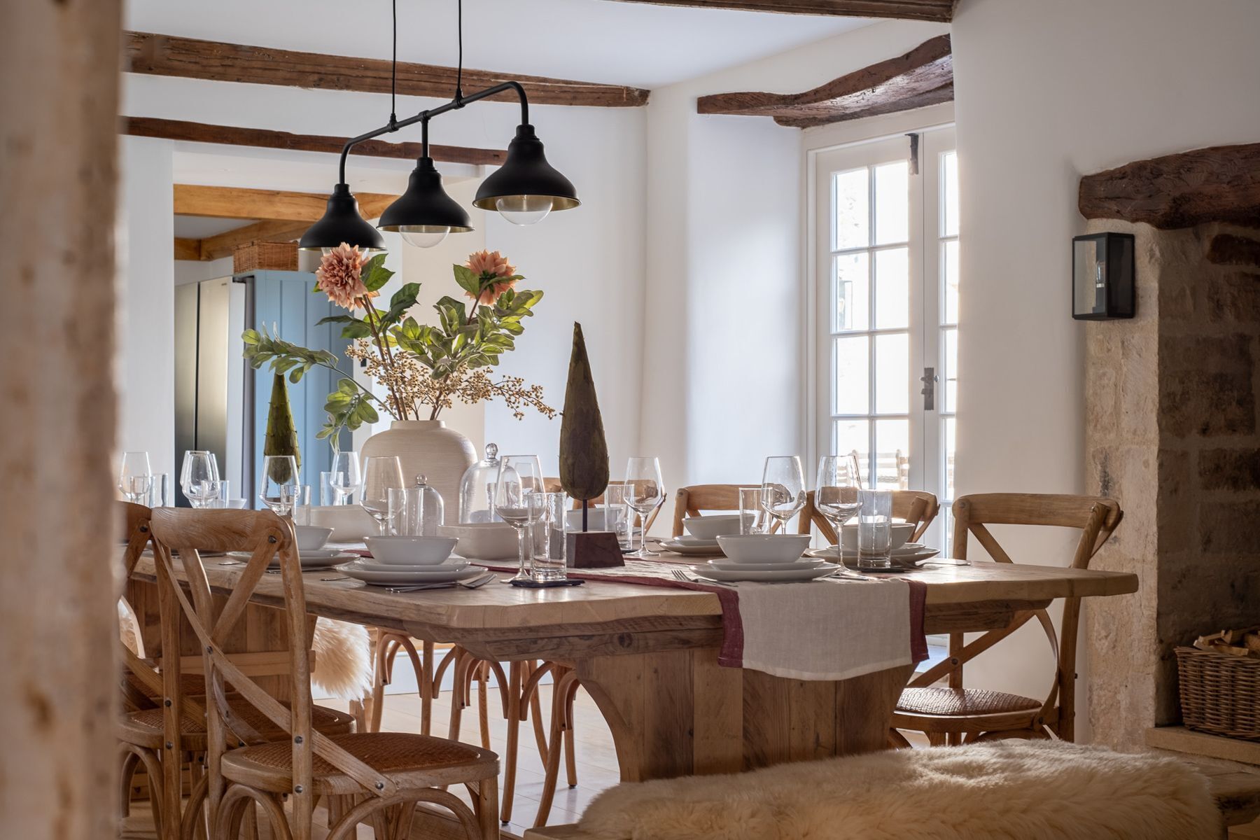 A dining area with a wooden table, chairs, and hanging pendant lights.