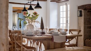Uma sala de jantar com mesa de madeira, cadeiras e luminárias pendentes.