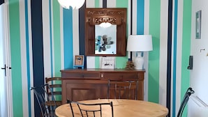 A dining area with a wooden table, chairs, a hanging light fixture, and a striped wall. - Quiet Orchard Retreat 10 Minutes from the Beach (Quiberon)