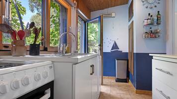 A compact kitchen with a built-in stove, a sink, and a window overlooking greenery.
