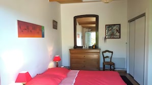 A bedroom with a bed, dresser, chair, and artwork on the walls. - Quiet Orchard Retreat 10 Minutes from the Beach (Quiberon)