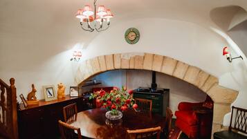Comedor con chimenea de piedra, muebles de madera y una lámpara de araña.