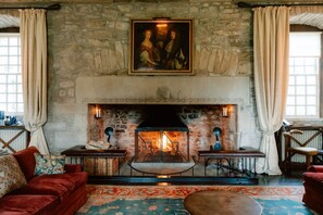 A room with a stone fireplace, a painting above it, and a red sofa.