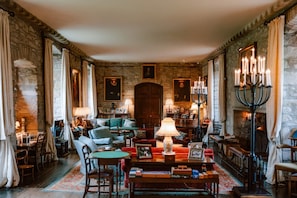 A traditional room with stone walls, a fireplace, and a cozy seating area with a table and chairs.