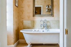 Una vasca da bagno vintage con zampette, un rubinetto moderno, un piccolo sapolaio e uno specchio sopra.
