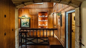 A wooden interior with a bench, a shelf with decorative items, and a framed picture.