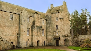 Un bâtiment historique en pierre, doté de nombreuses fenêtres et d’une tour centrale.
